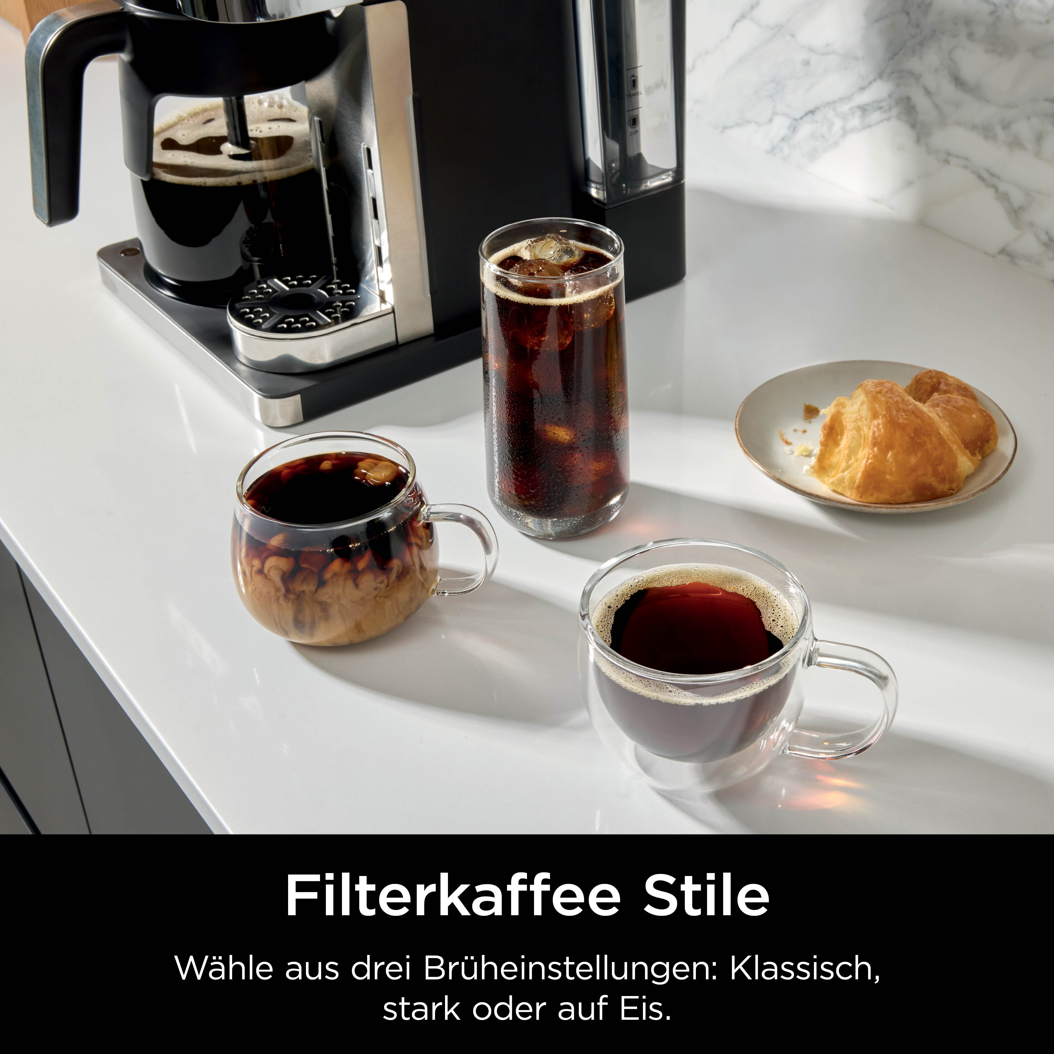 Macchina da caffè con tre tipi di caffè e pasticcini su un piano di lavoro in marmo.