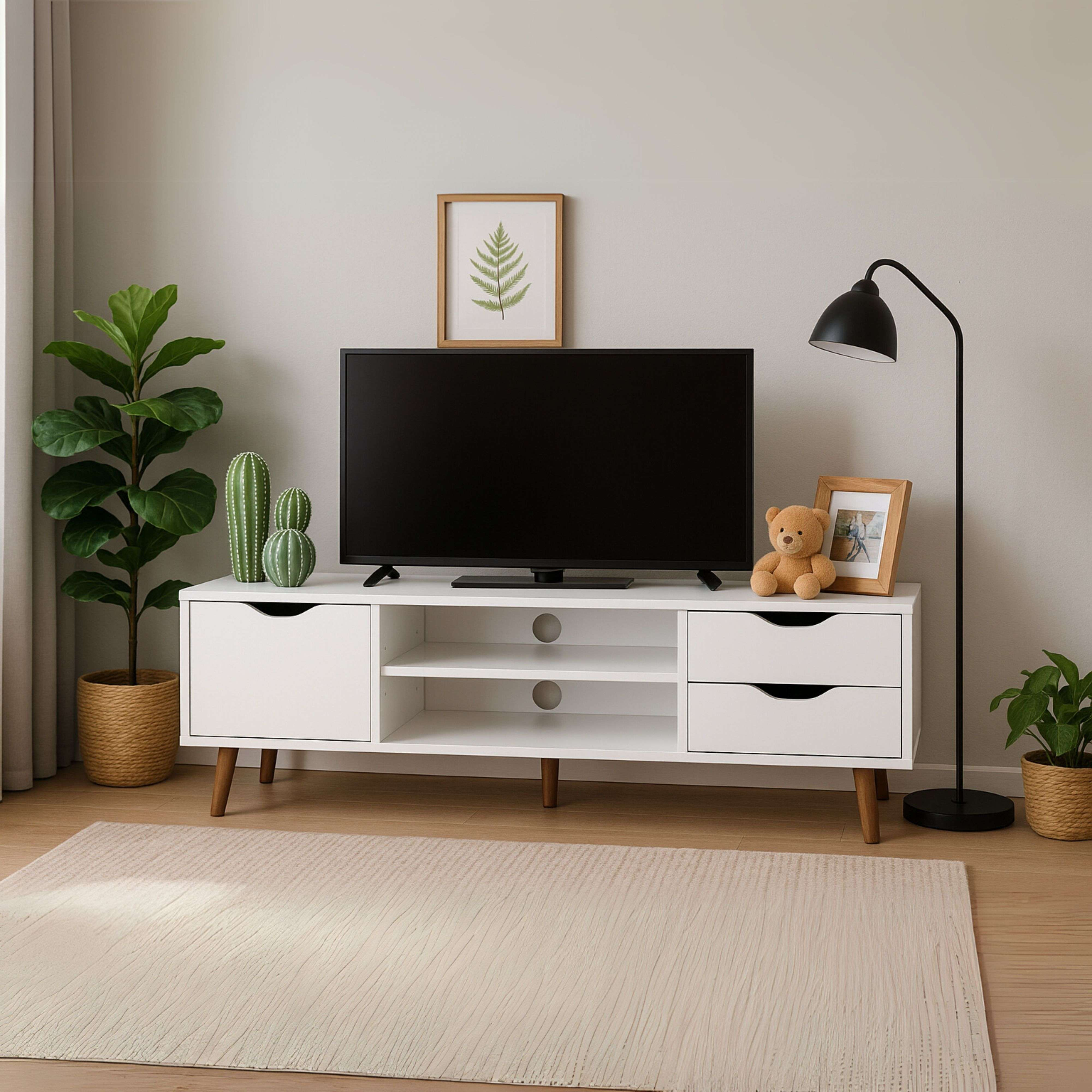 Un mueble de TV blanco con TV, plantas y un oso de peluche.