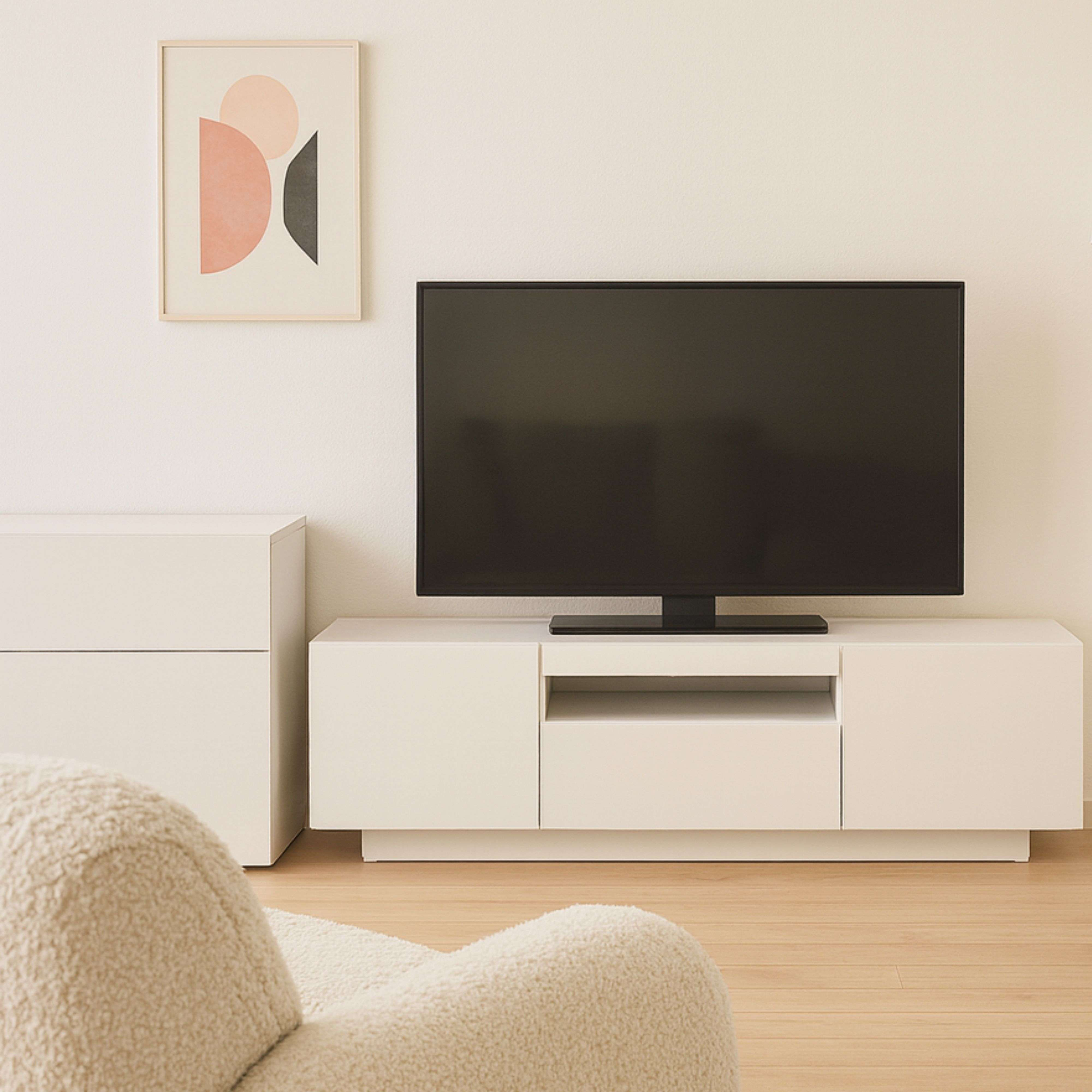 Un mueble bajo blanco con un televisor y una obra de arte en la pared.