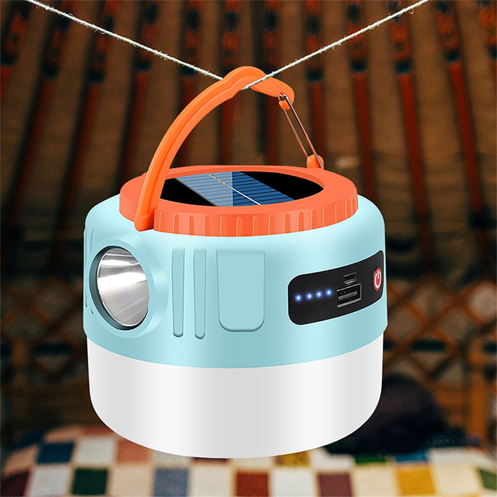 Eine blau-weiße Campinglaterne mit orangefarbenem Griff hängt an einer Schnur. Sie hat ein Solarpanel.