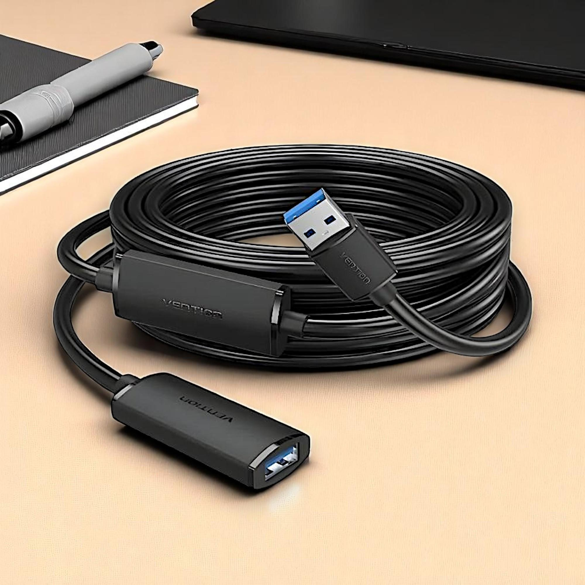 Cable de extensión USB negro con conectores hembra y macho sobre mesa.