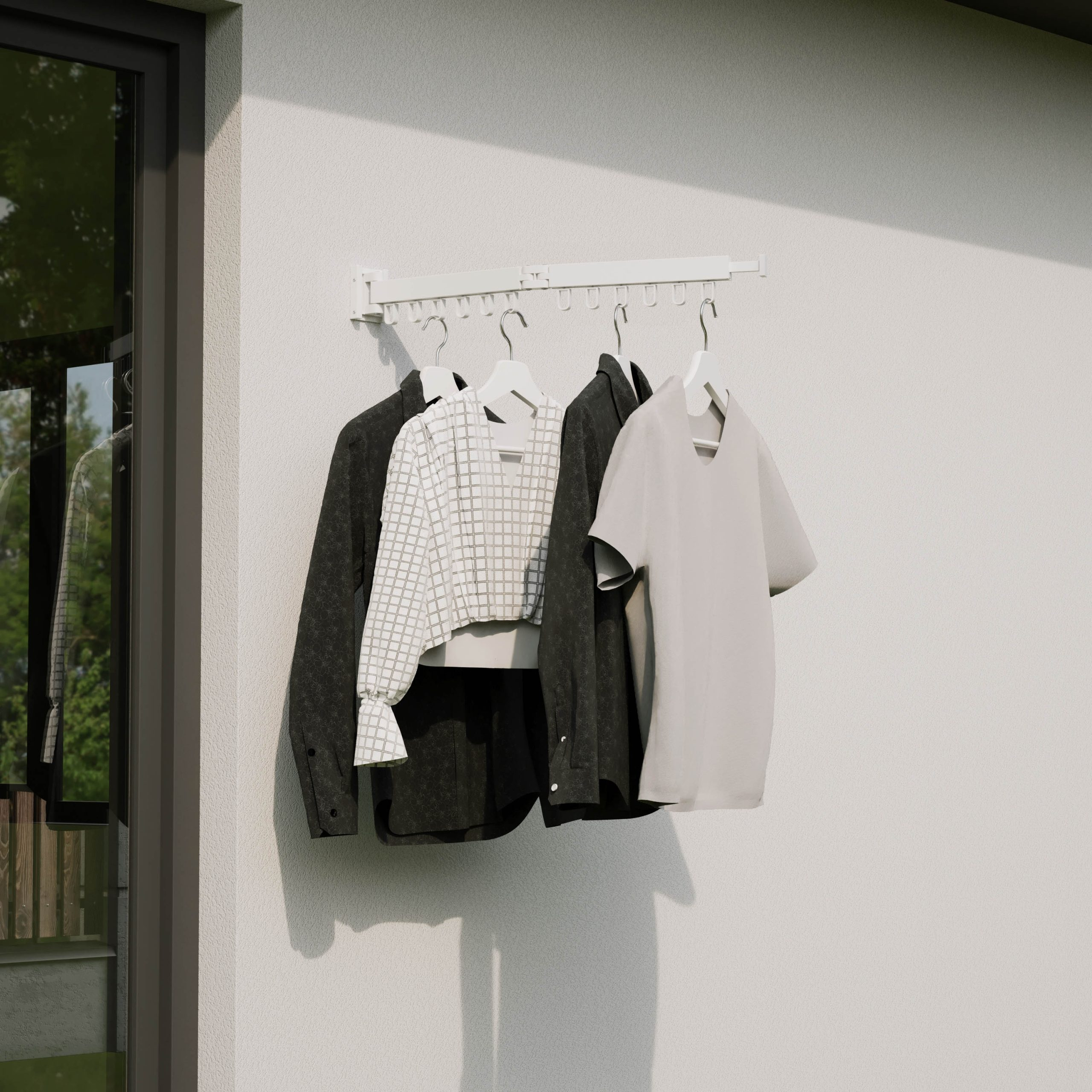 Quatre vêtements sont suspendus à un étendoir blanc contre un mur.