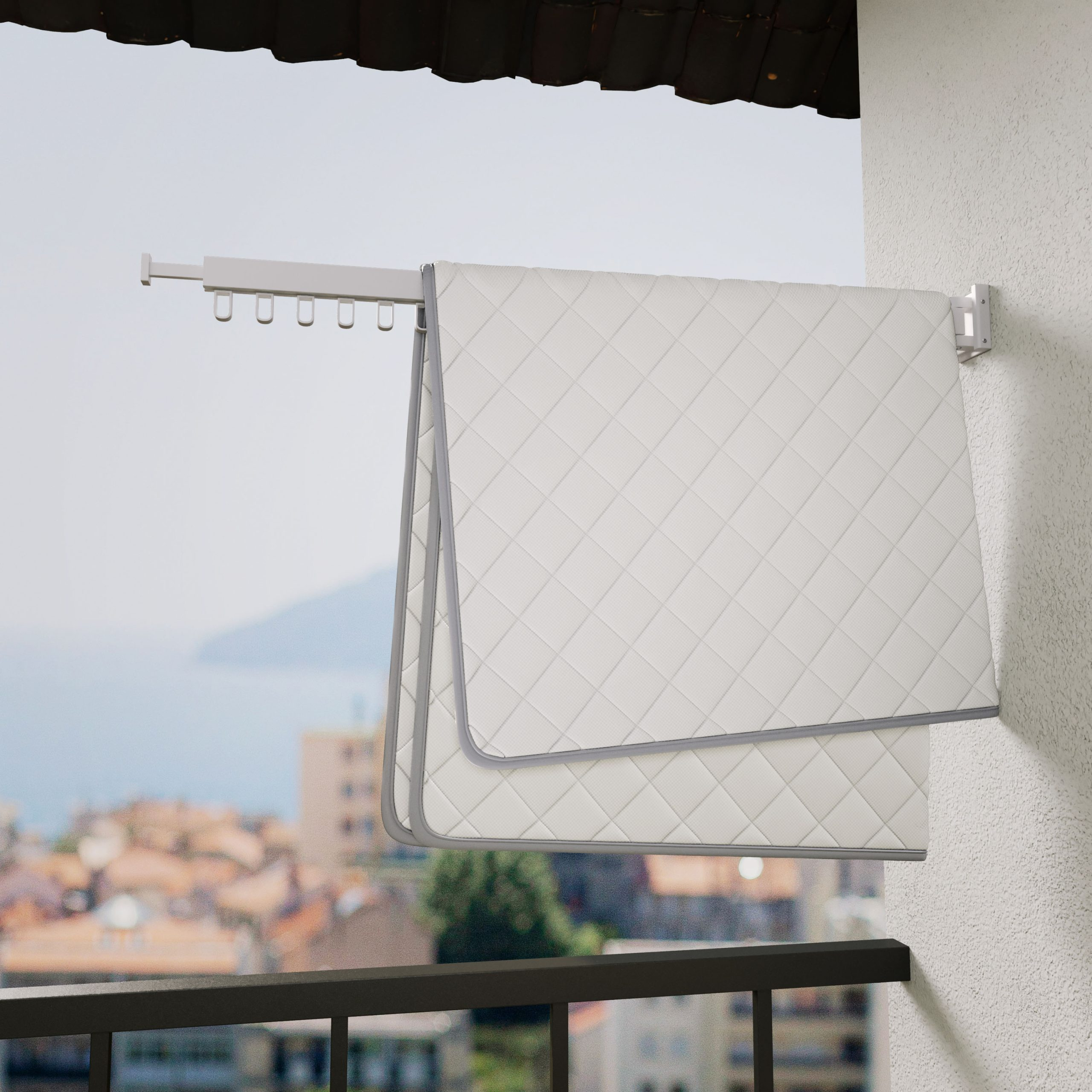 Couverture matelassée blanche à bordure grise suspendue à un étendoir de balcon.