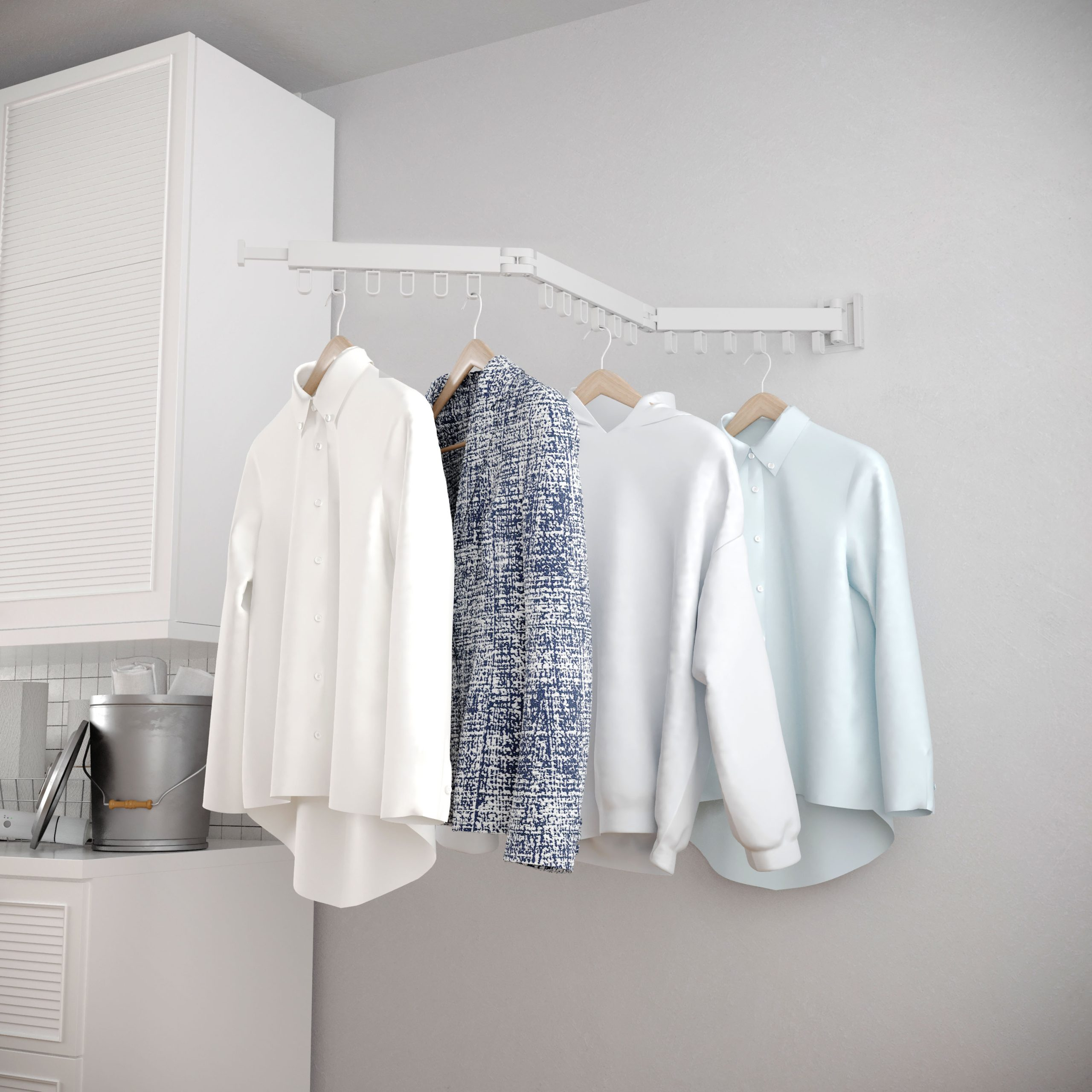Quatre chemises pendent sur des cintres sur un étendoir mural. Une chemise en tweed bleu et blanc.