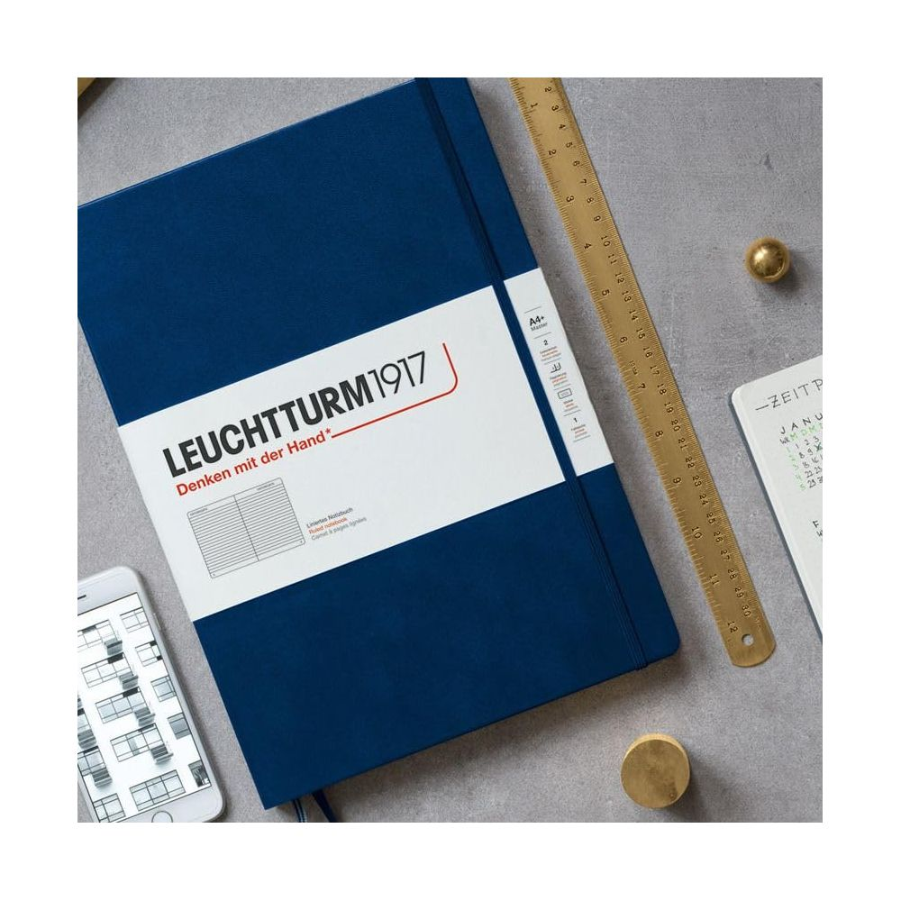 Un carnet bleu foncé Leuchtturm1917 repose à côté d'un smartphone et d'une règle.