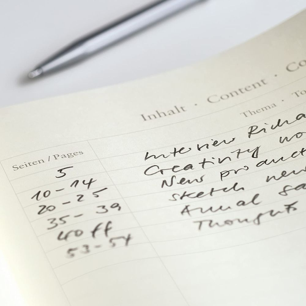 Ein Notizbuch mit einer Liste von Themen und Seitenzahlen, daneben ein Stift.