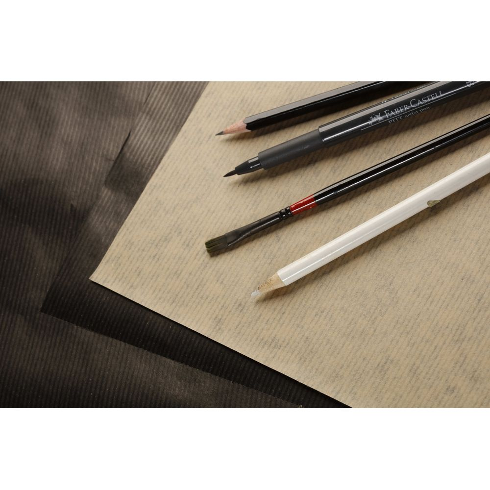 Zeichenwerkzeuge liegen auf braunem Papier: Bleistift, Filzstift, Pinsel, weißer Stift.