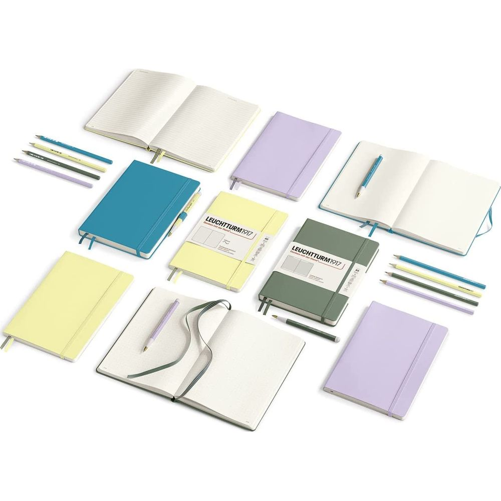 Viele Notizbücher in Pastellfarben und Stifte auf weißem Hintergrund.