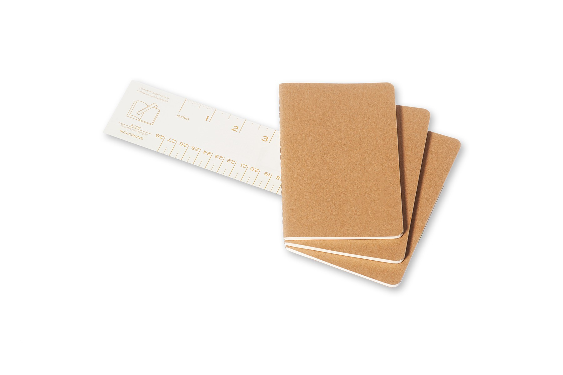 Trois carnets marron à côté d'une règle graduée en pouces et en centimètres.