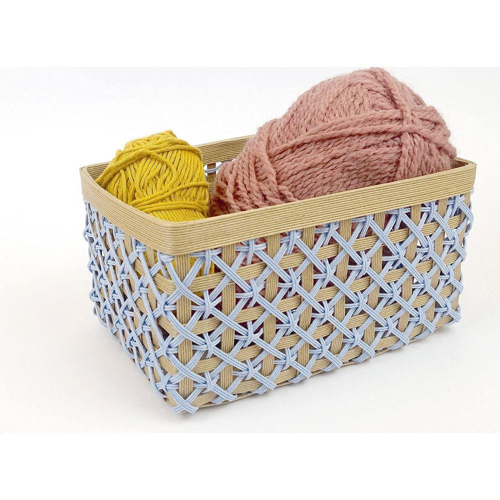 Un panier tressé contenant deux pelotes de laine : une jaune, une rose poudré.