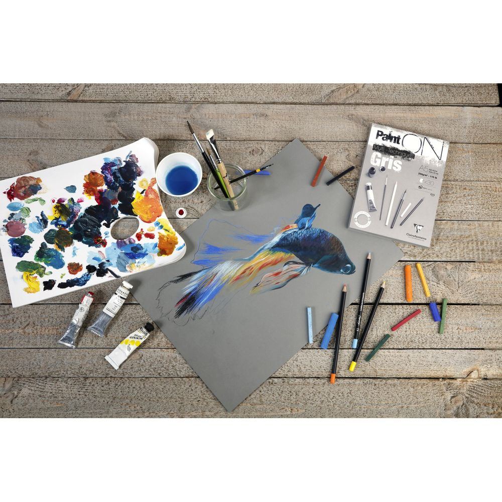 Disegno di pesce combattente su carta grigia con tavolozza, matite e pastelli.