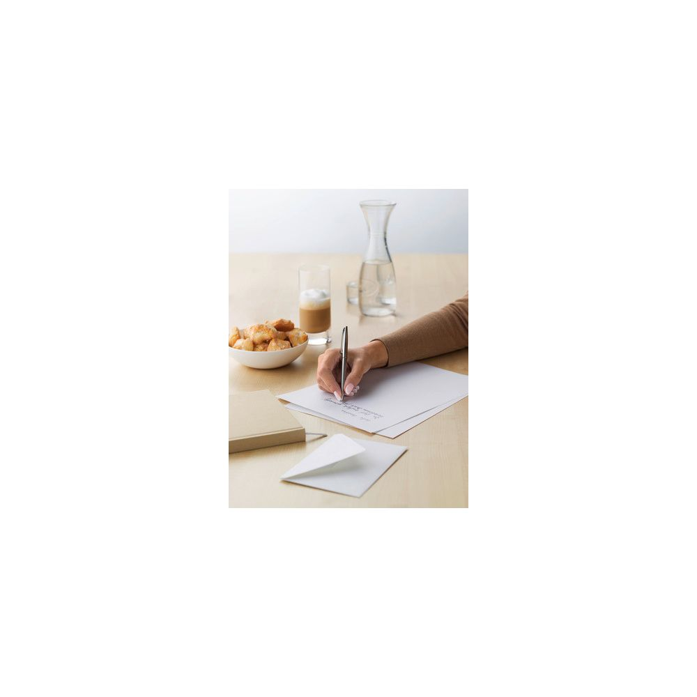 Eine Hand schreibt auf Papier, daneben ein Glas Kaffee, Kekse und Wasser.
