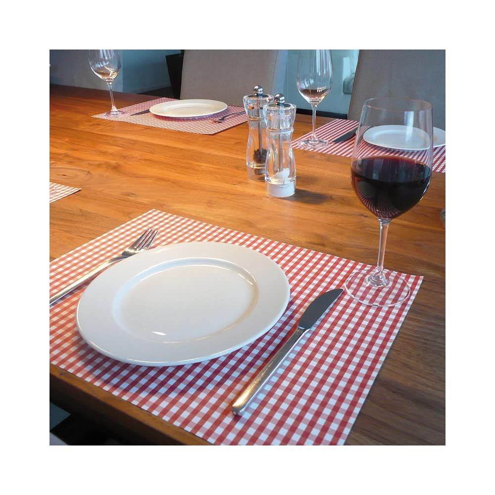 Table en bois dressée avec nappe à carreaux vichy rouges, assiette, couverts, verre de vin rouge.