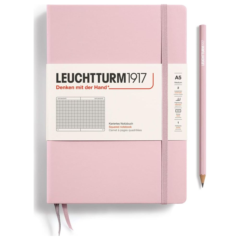 Un quaderno rosa con elastico e una matita abbinata sono affiancati.