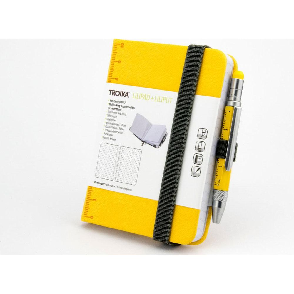 Un carnet jaune avec stylo et règle. Fermé par un élastique.