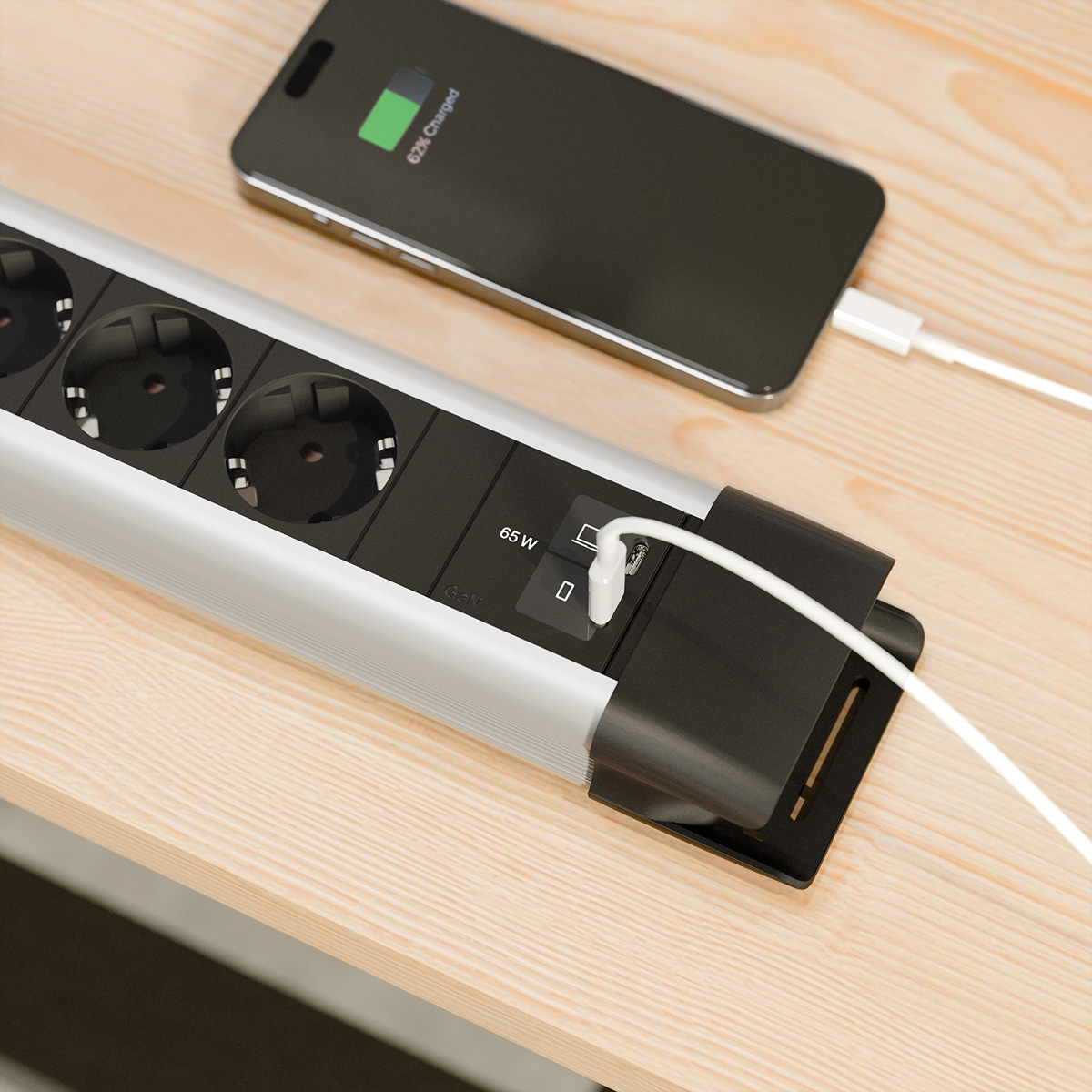 Ein Smartphone wird über ein weißes Kabel an eine Mehrfachsteckdose geladen.
