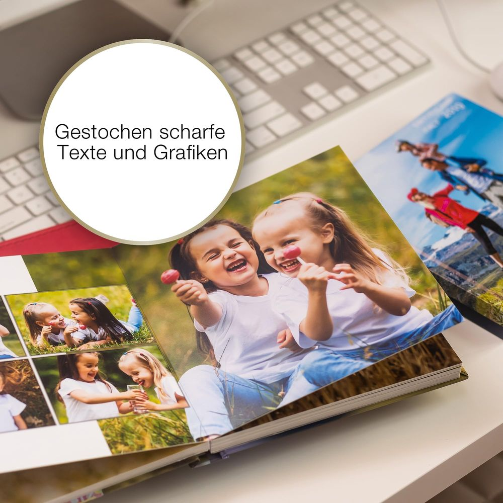 Zwei lachende Mädchen mit Lollis vor einem Fotoalbum und Tastatur.