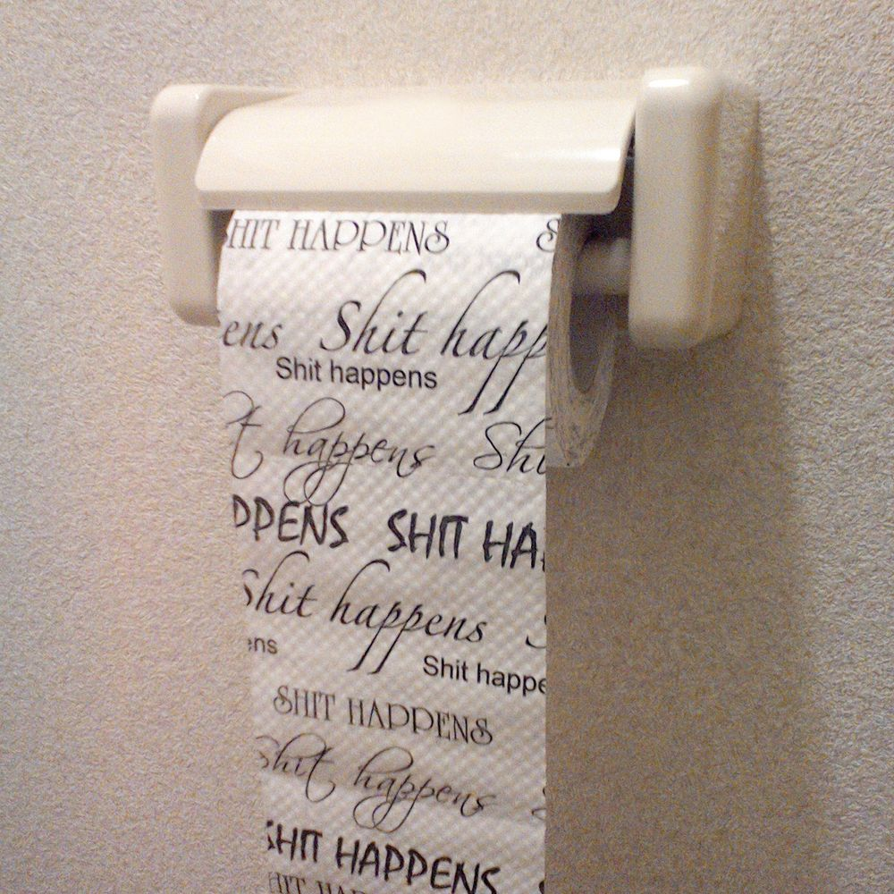 Toilettenpapier mit der Aufschrift „Shit happens“ in einem Halter.