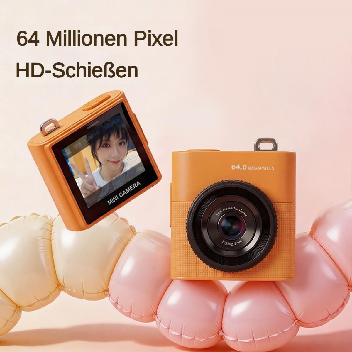 Zwei orangefarbene Mini-Kameras, eine mit Selbstporträt, auf rosa und gelben Kissen.