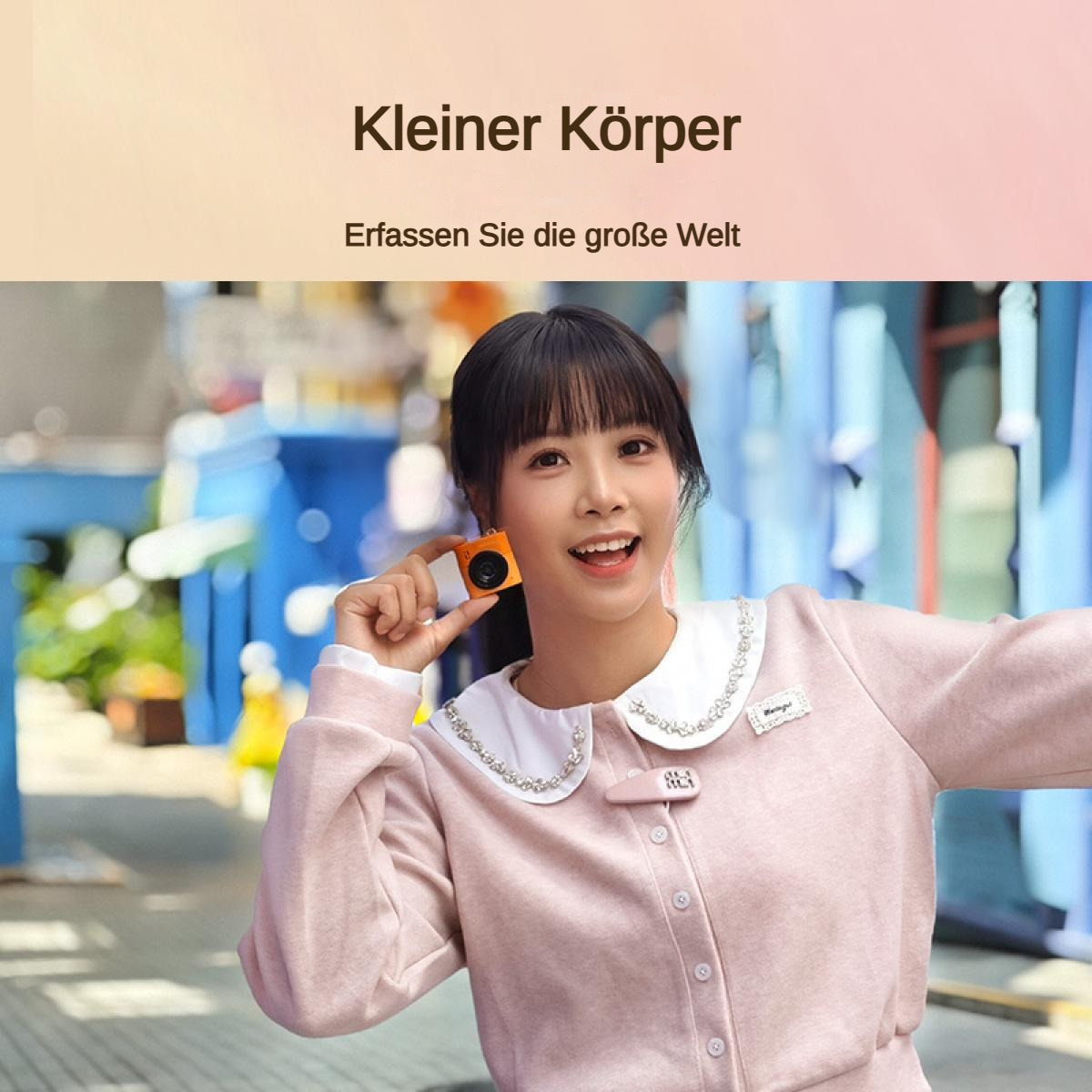 Eine junge Frau hält eine winzige orangefarbene Kamera.