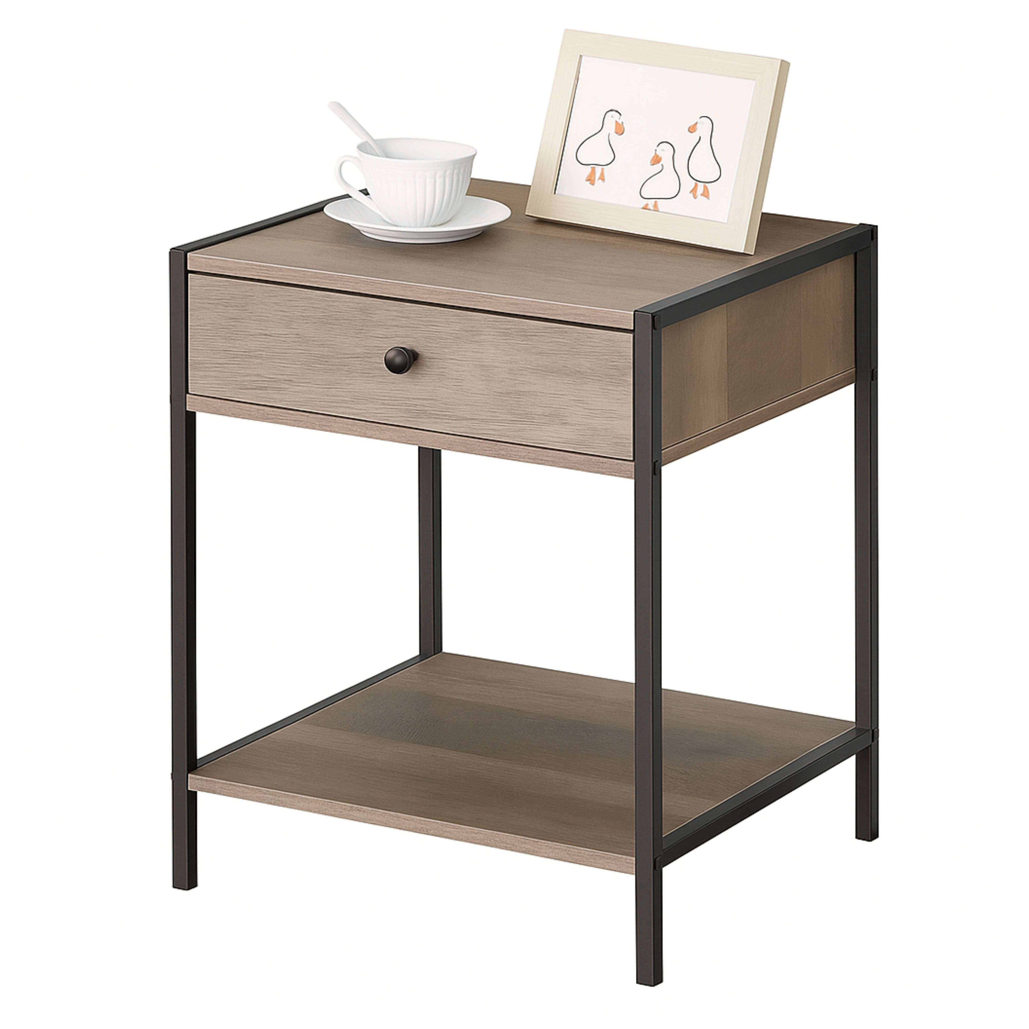 Una mesita de noche de madera con cajón, taza y cuadro de patos.