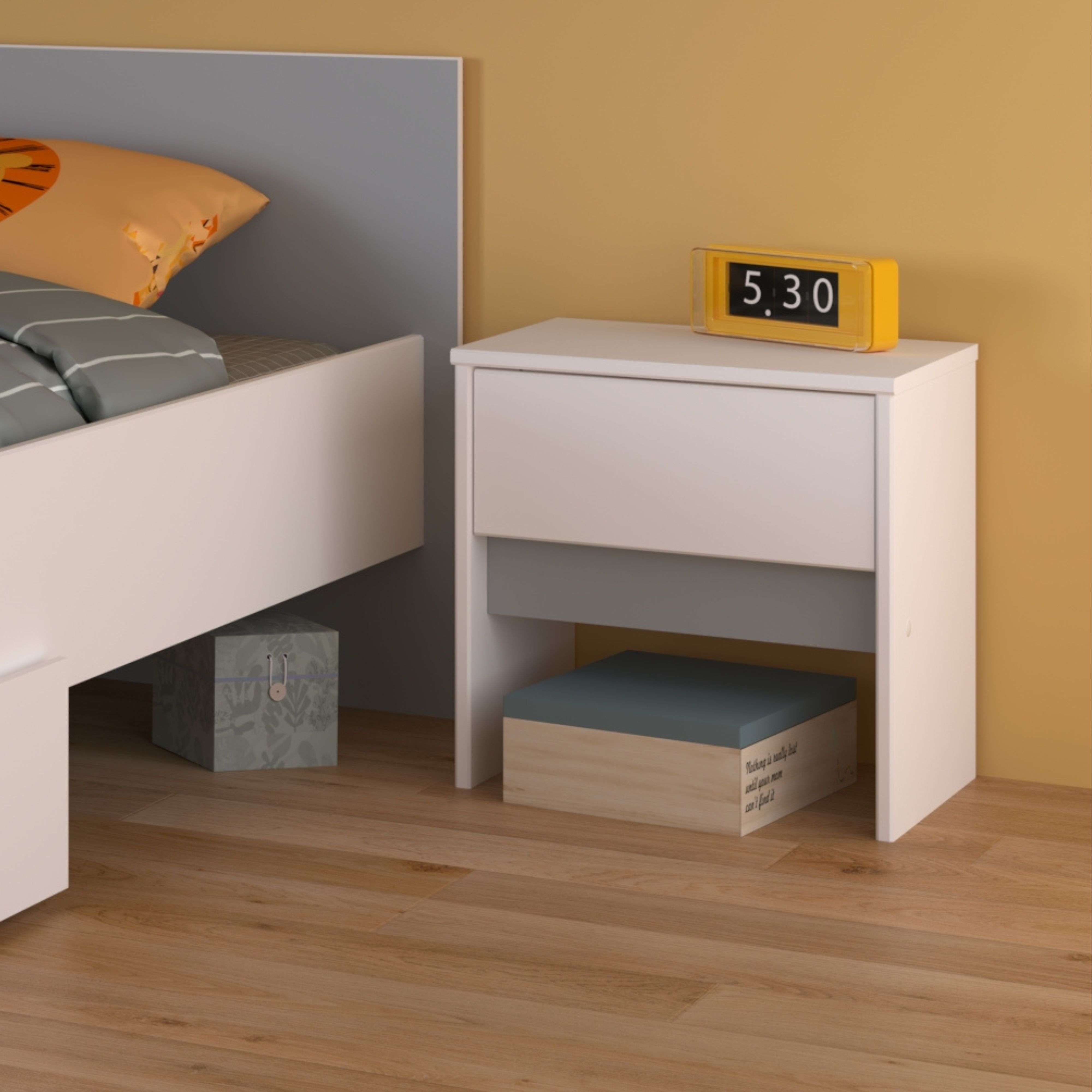 Una mesita de noche con cajones junto a una cama con ropa de cama a rayas.