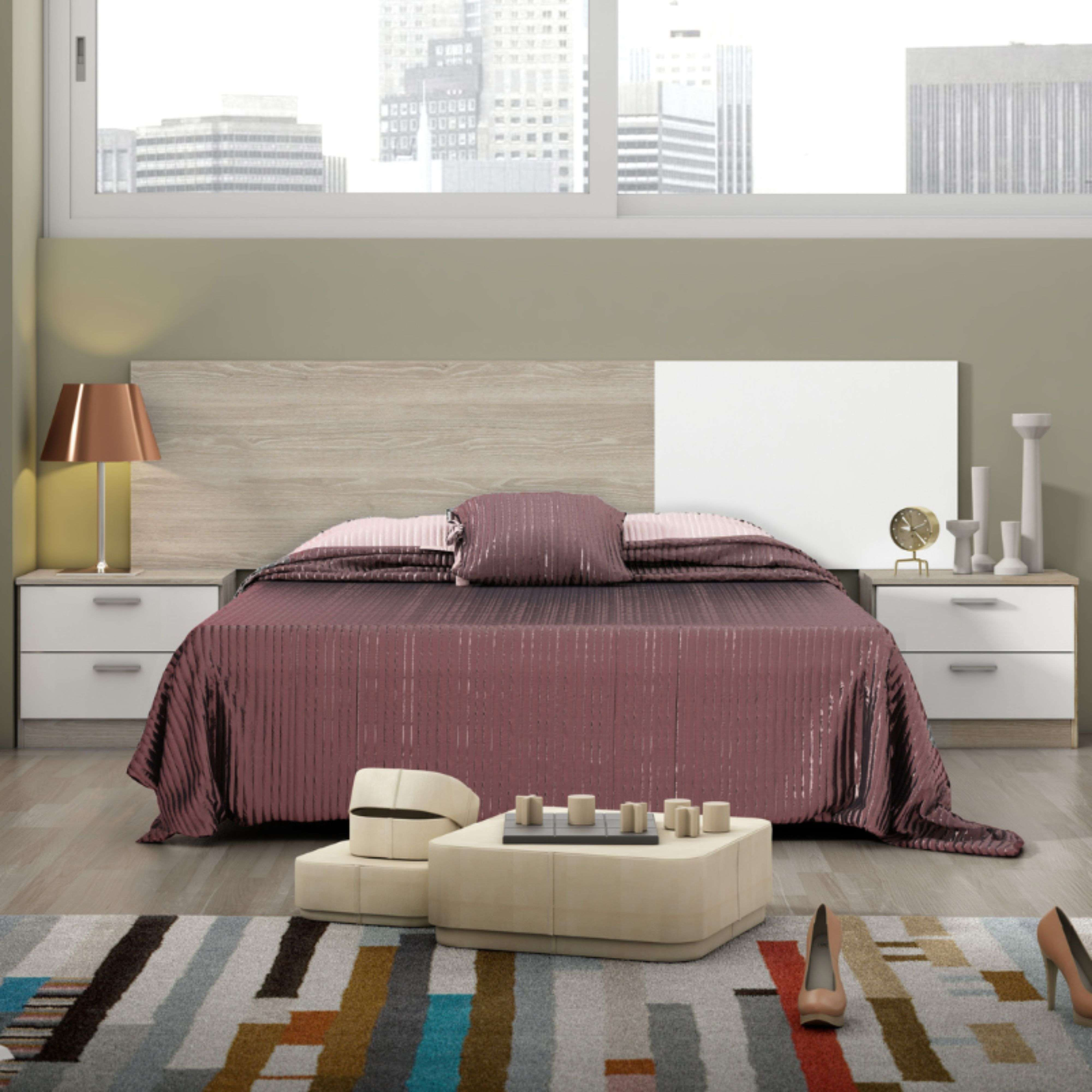 Un dormitorio con vista a la ciudad por la noche. Una cama grande con ropa de cama morada.