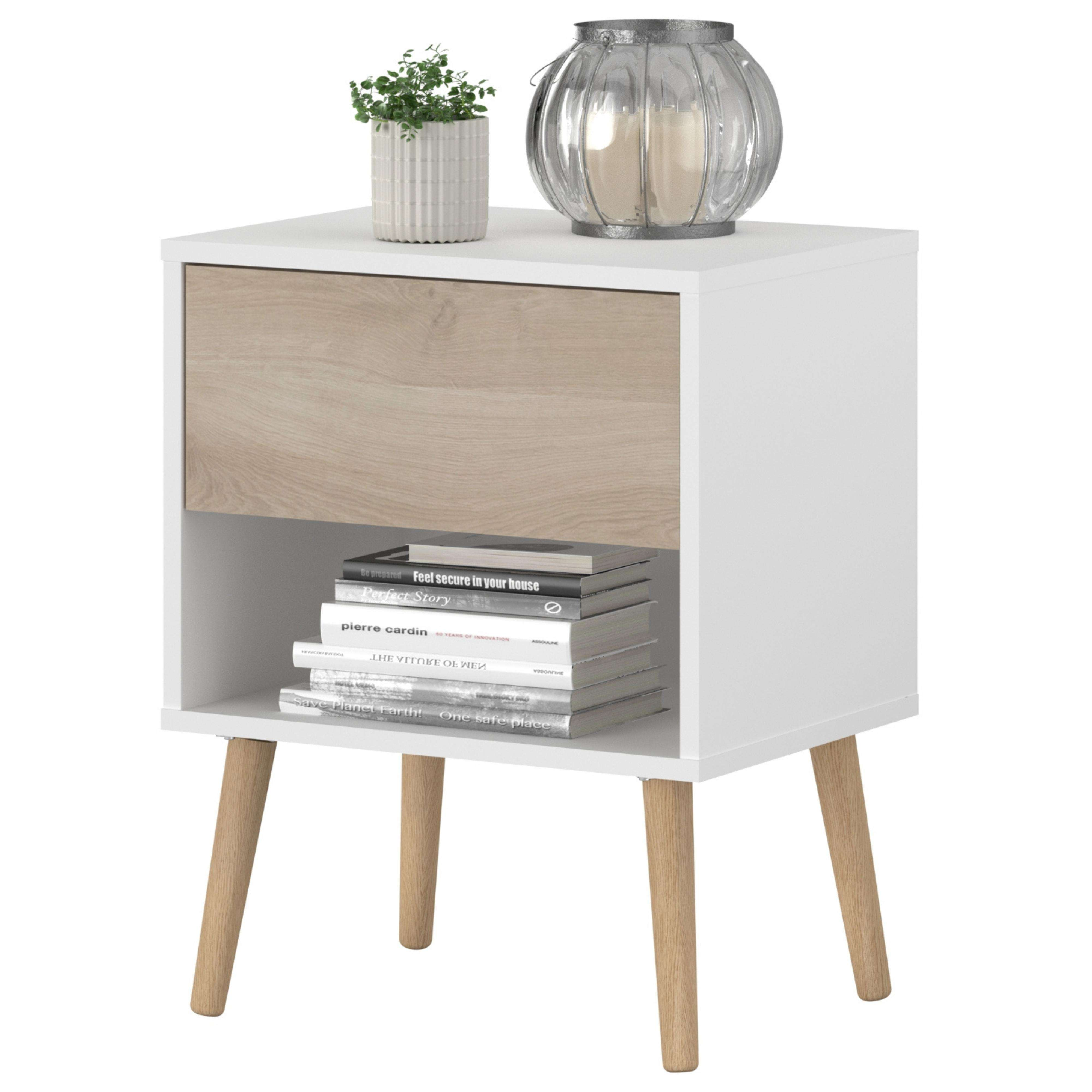 Mesita de noche blanca con cajón de madera, estante, libros, planta y linterna.