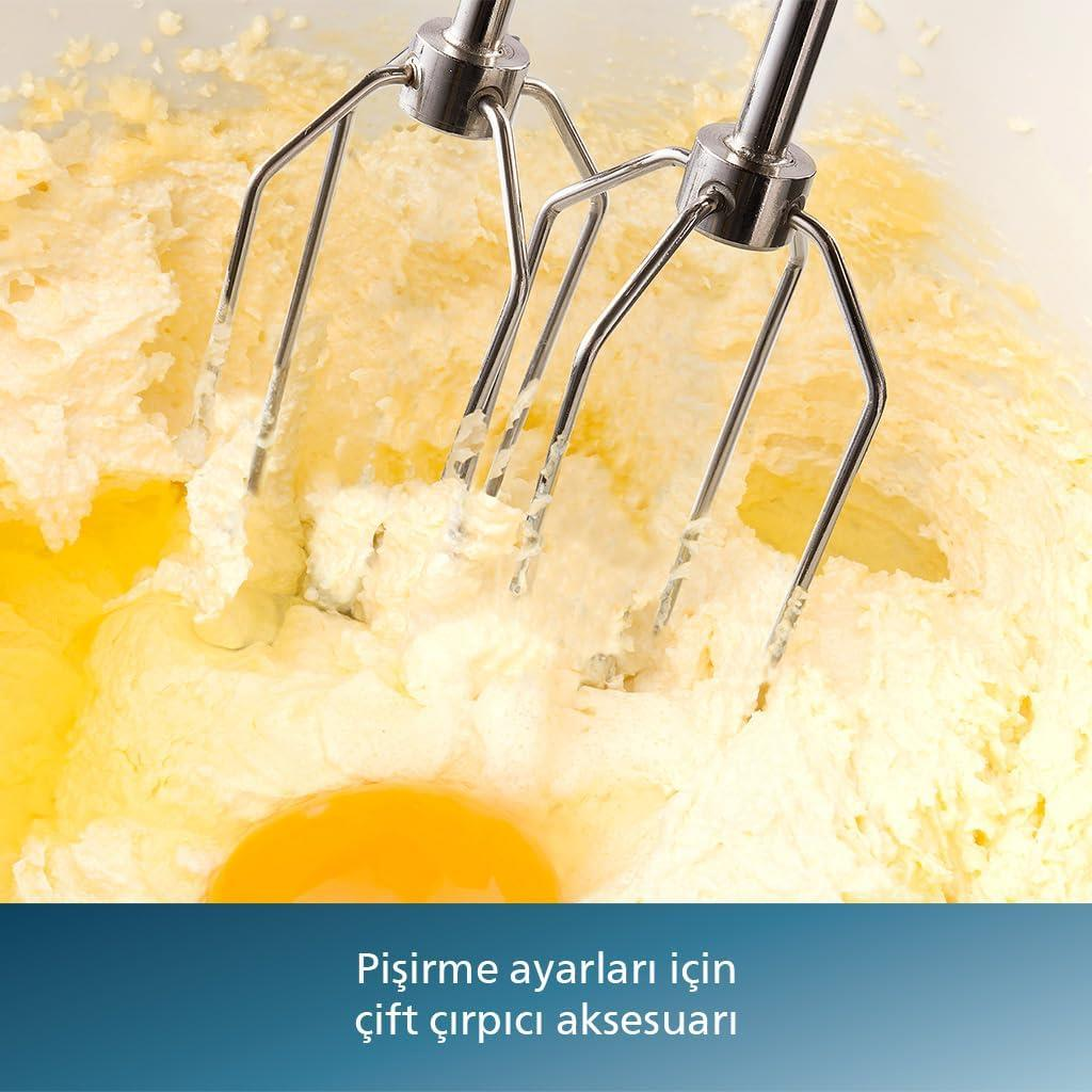 İki çırpıcıya sahip el mikseri, bir kapta bir yumurta sarısı ile sarı bir hamur karıştırıyor.