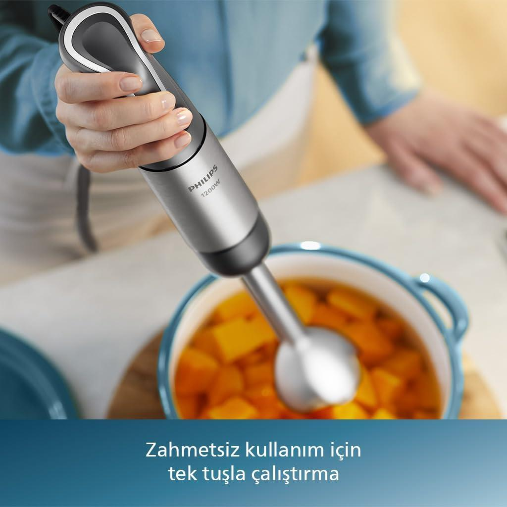 Kişi, balkabağı parçaları olan bir tencerede gümüş renkli el blenderi kullanıyor.
