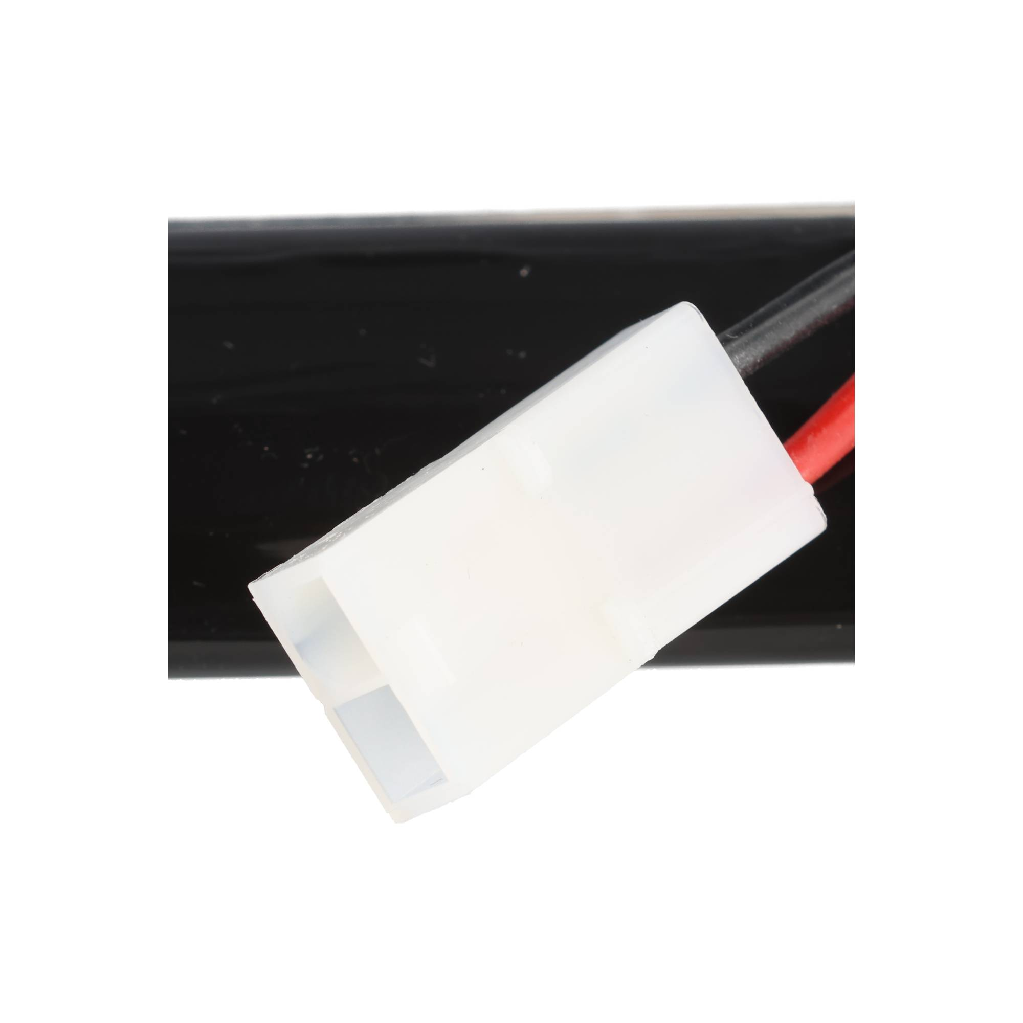 Ein weißer Stecker mit roten und schwarzen Kabeln an einem schwarzen Objekt.