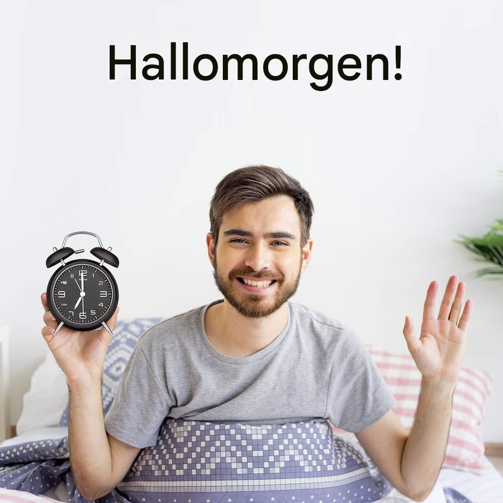 Ein Mann im Bett hält einen Wecker und winkt.