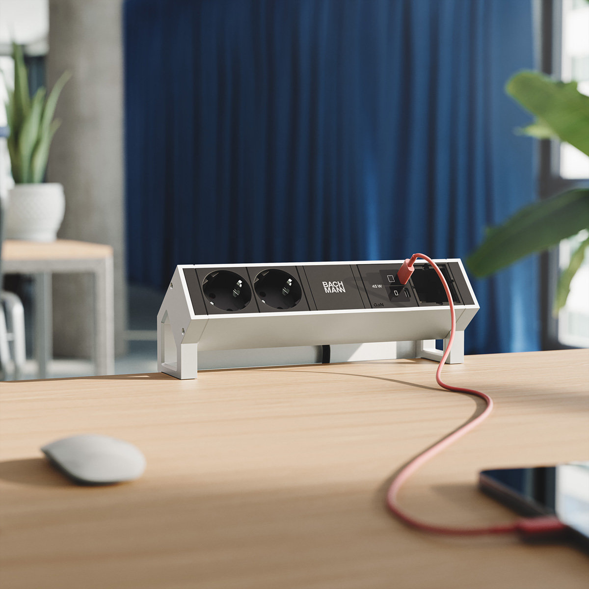 Eine weiße Steckdosenleiste mit zwei Steckplätzen und USB-Ports auf einem Schreibtisch.