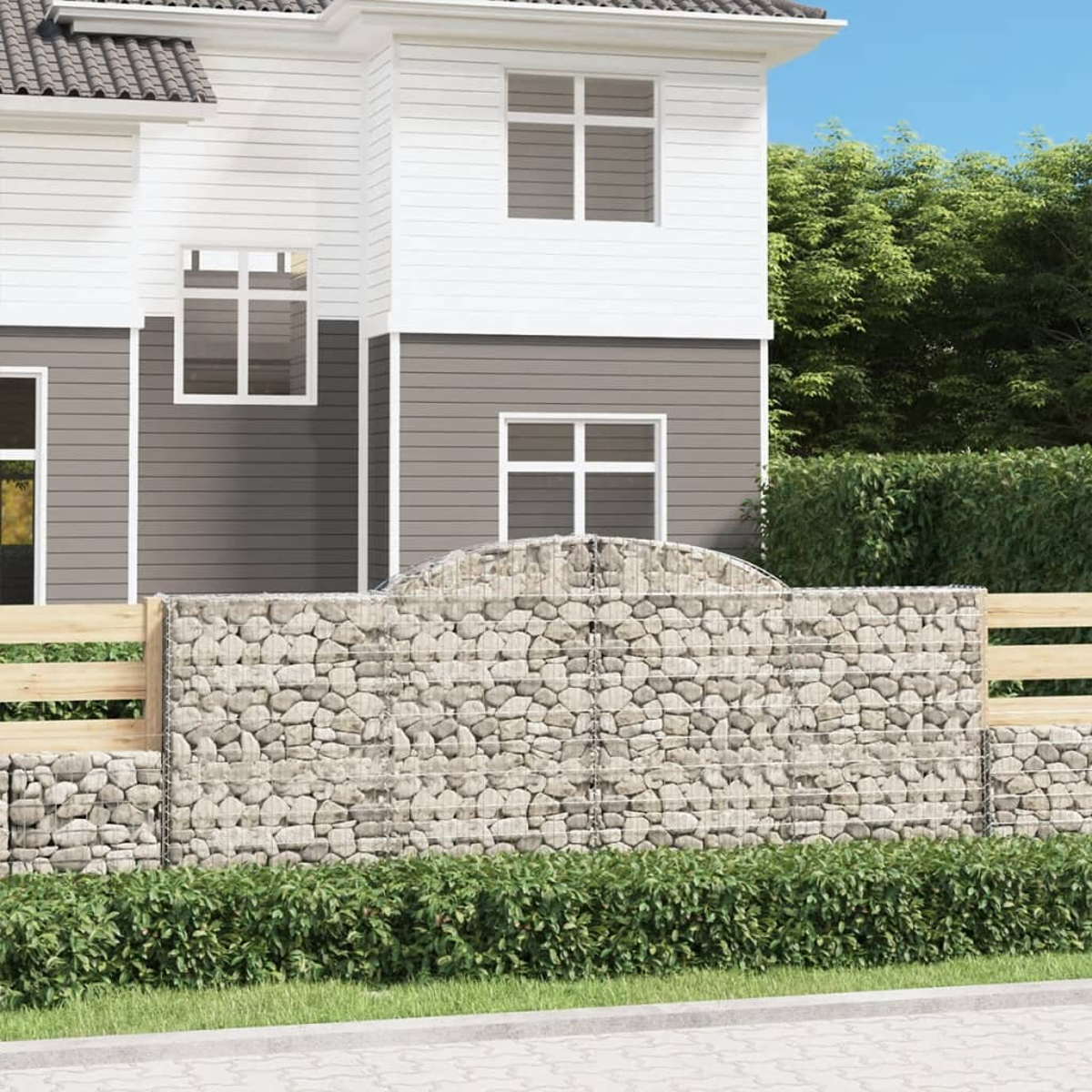 Ein modernes Haus mit weißer und grauer Verkleidung und Gabionenmauer.