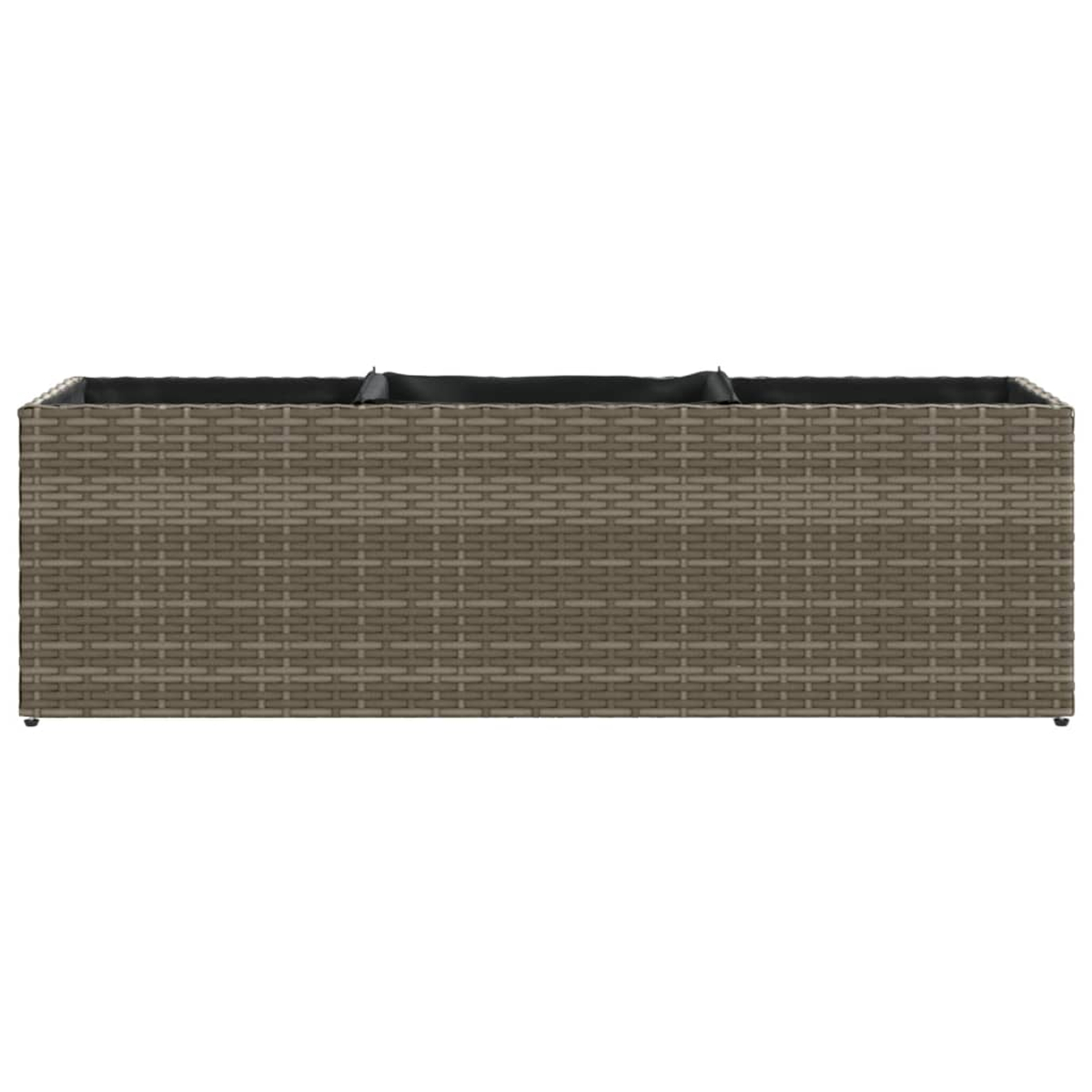 Brauner Rattansofa mit schwarzen Kissen.