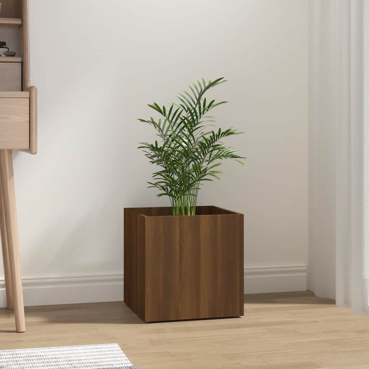 Ein brauner Holzwürfel-Blumentopf mit einer grünen Pflanze steht auf einem Holzboden.