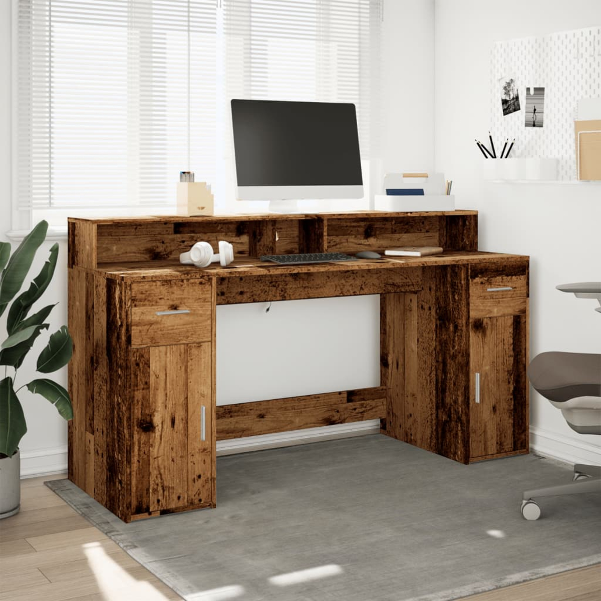 Ein hölzerner Schreibtisch mit einem Monitor, Tastatur und Kopfhörern.