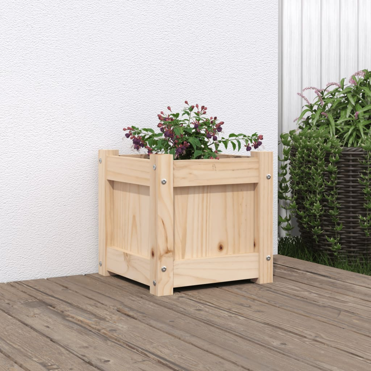 Ein Holzkübel mit einer blühenden Pflanze steht auf einer Holzterrasse neben einer Mauer.