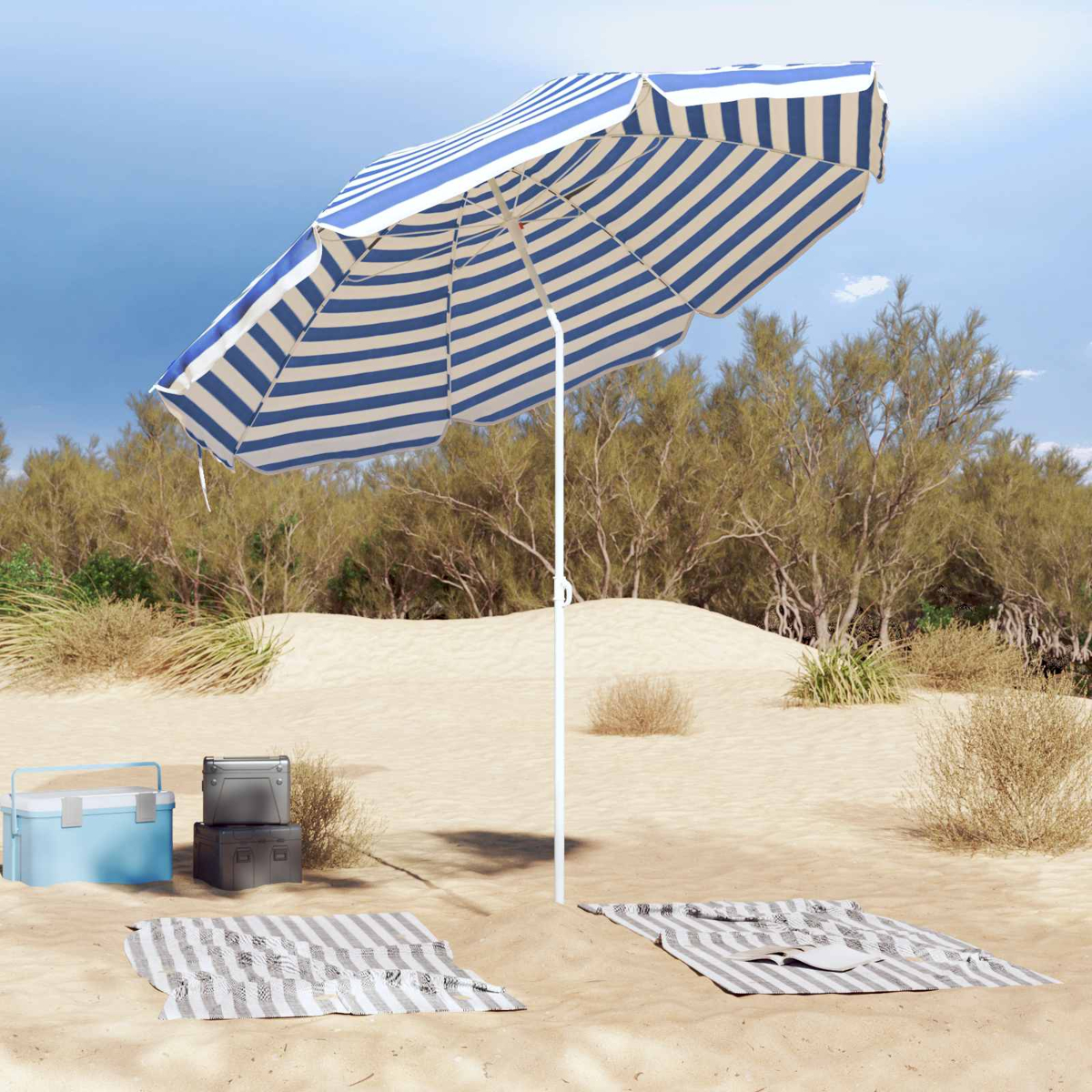 Ein blau-weiß gestreifter Sonnenschirm steht am Strand. Kühltaschen und Decken liegen im Sand.