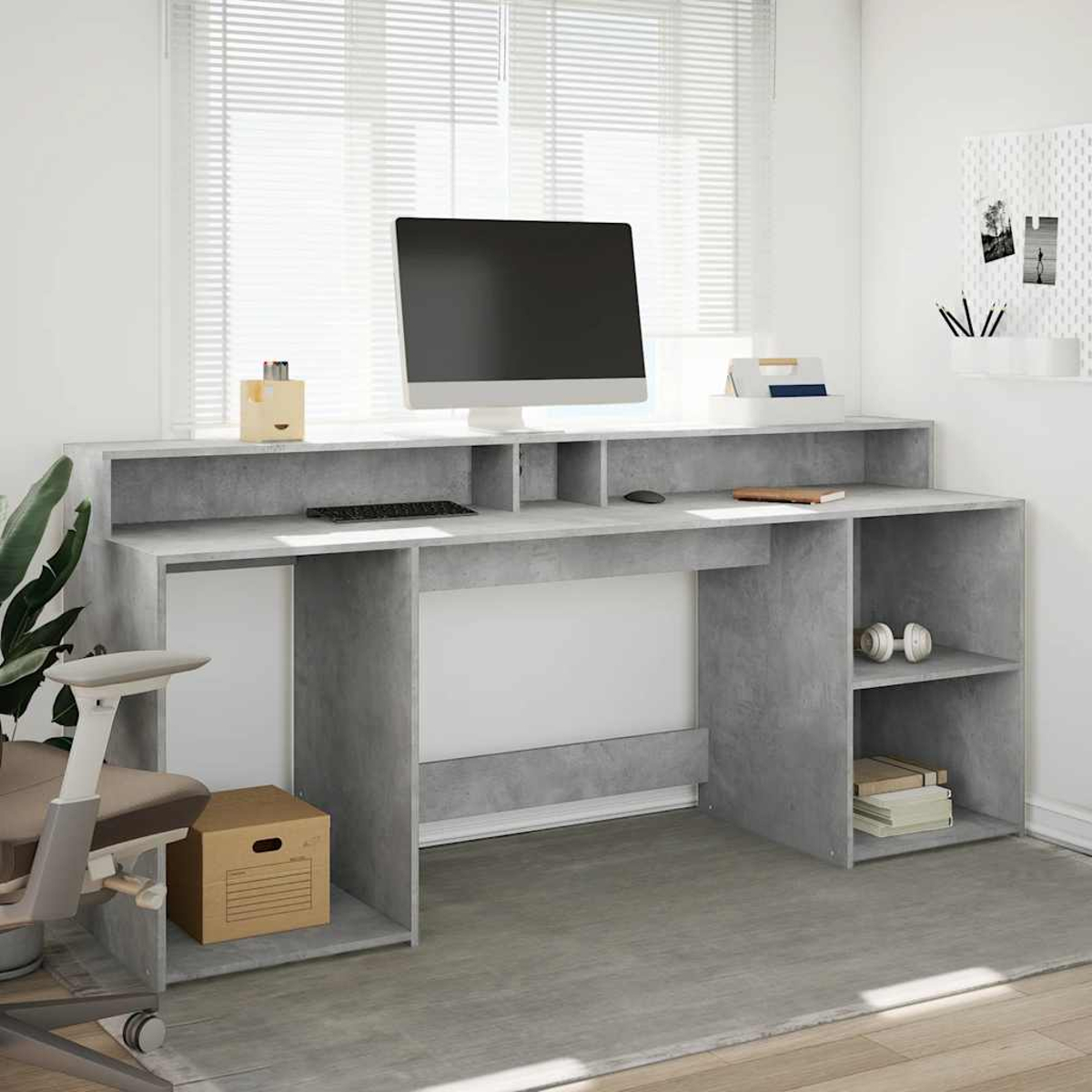 Ein moderner grauer Schreibtisch mit Computer, Tastatur und Kopfhörern. Stuhl und Kiste daneben.