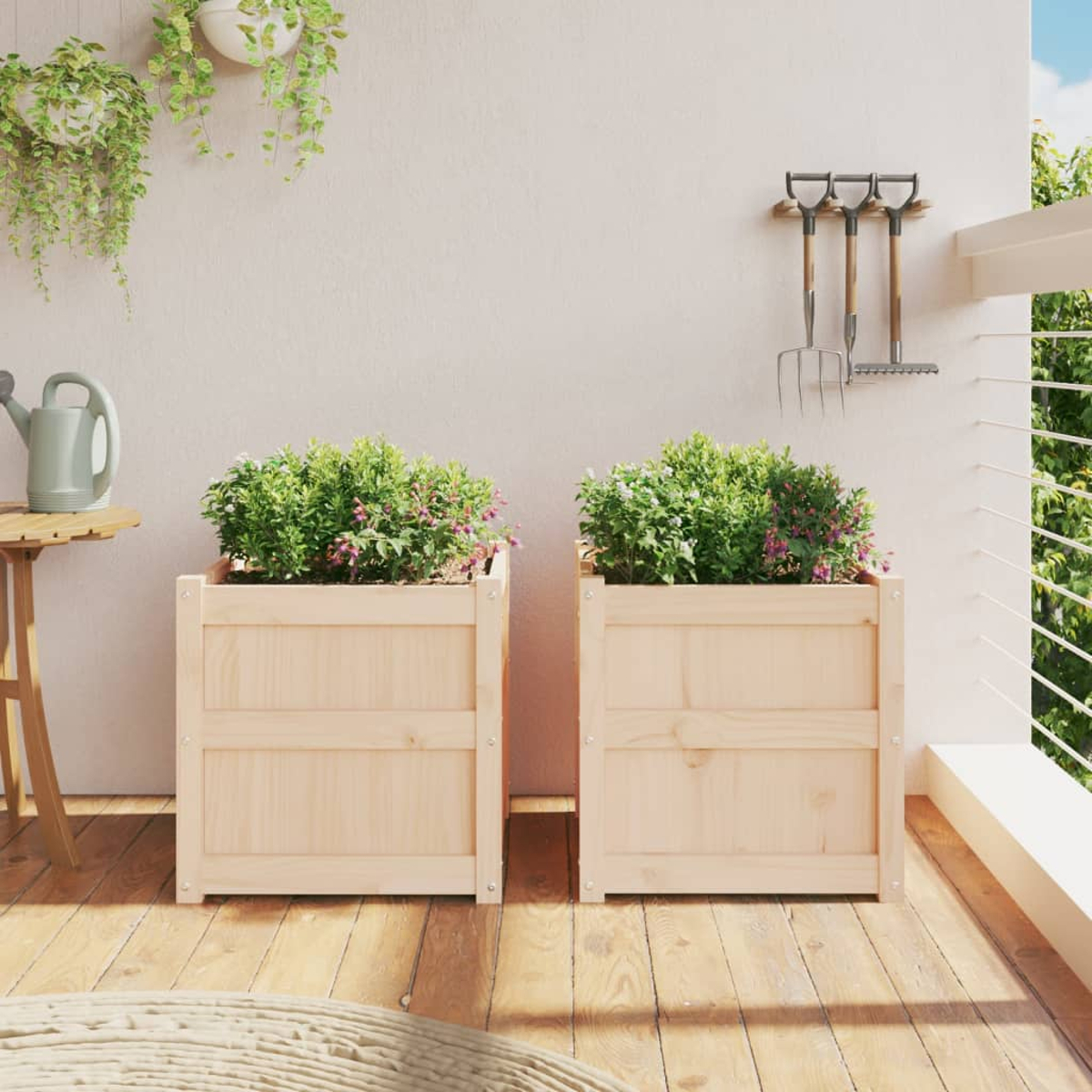 Zwei hölzerne Pflanzkübel mit grünen Pflanzen und rosa Blüten auf einer Holzterrasse.