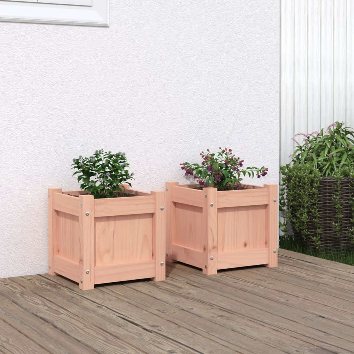 Zwei Holzpflanzkästen mit Pflanzen auf einer Holzterrasse vor weißer Wand.