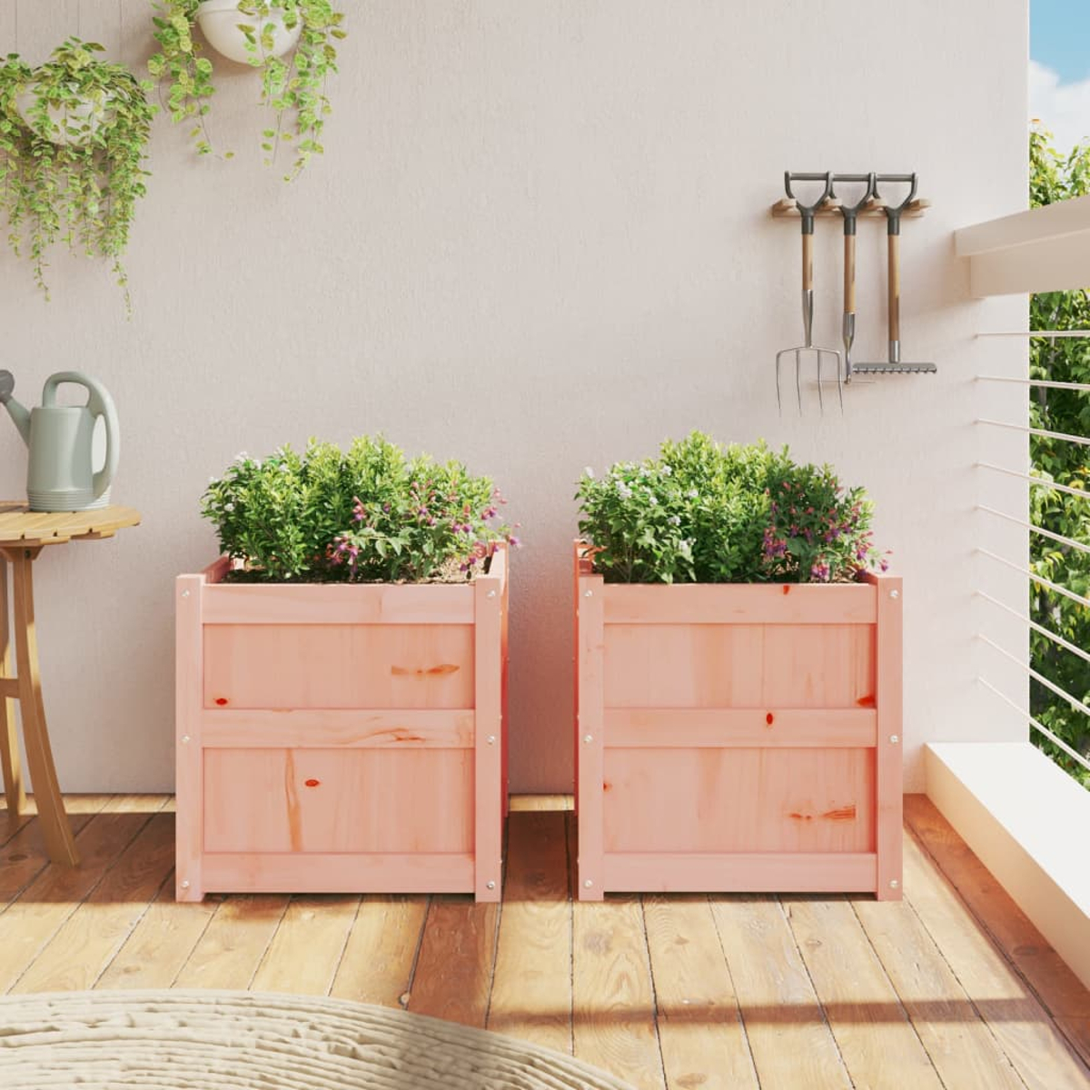 Zwei rosa Holzkübel mit Pflanzen auf einem Holzbalkon. Gartengeräte hängen an der Wand.