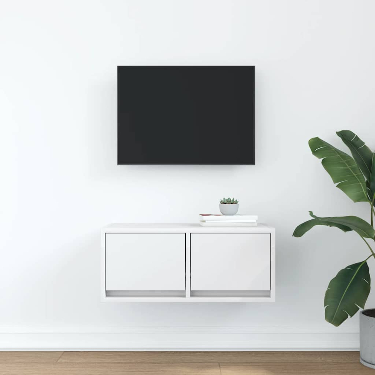 Ein schwarzer Fernseher über einem weißen Wandregal mit Pflanzen und Büchern.