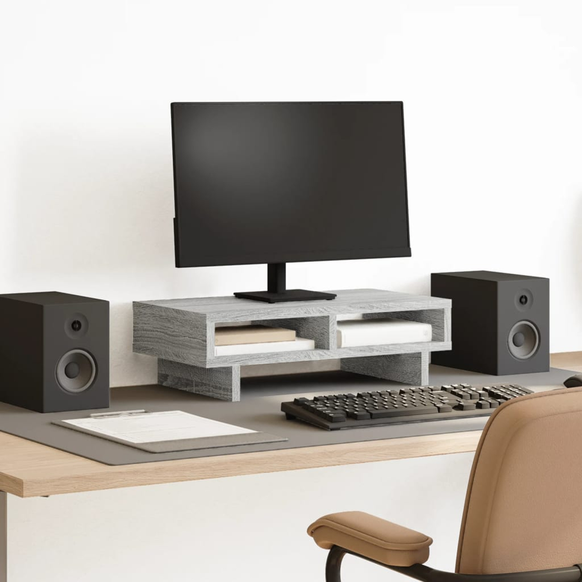Ein Schreibtisch mit einem Monitor, Tastatur, zwei Lautsprechern und einem Stuhl.