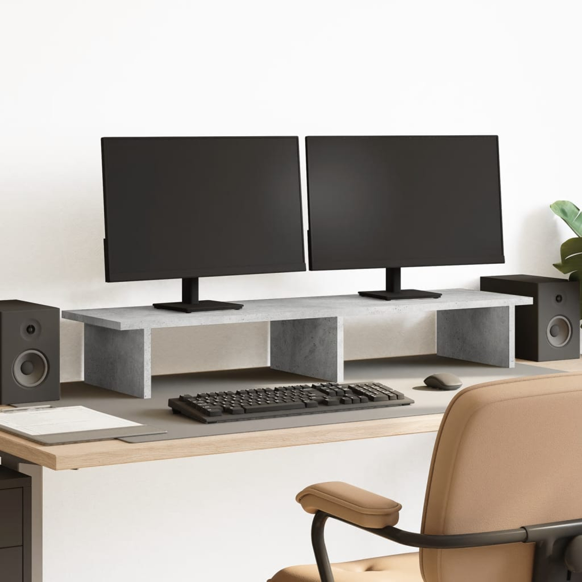 Zwei schwarze Monitore stehen auf einem grauen Sockel neben zwei schwarzen Lautsprechern.