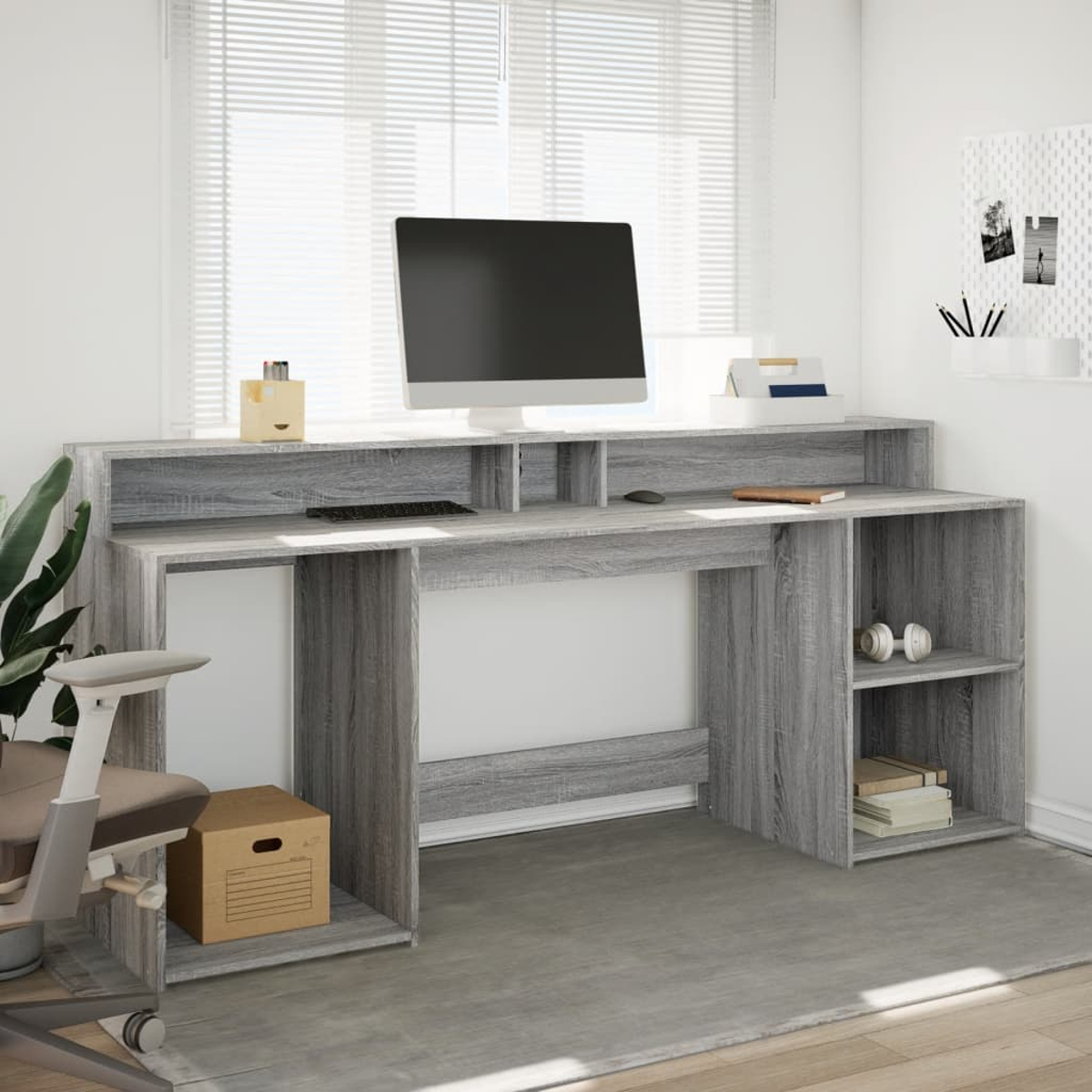 Ein grauer Schreibtisch mit einem Monitor, Tastatur und Bürostuhl.