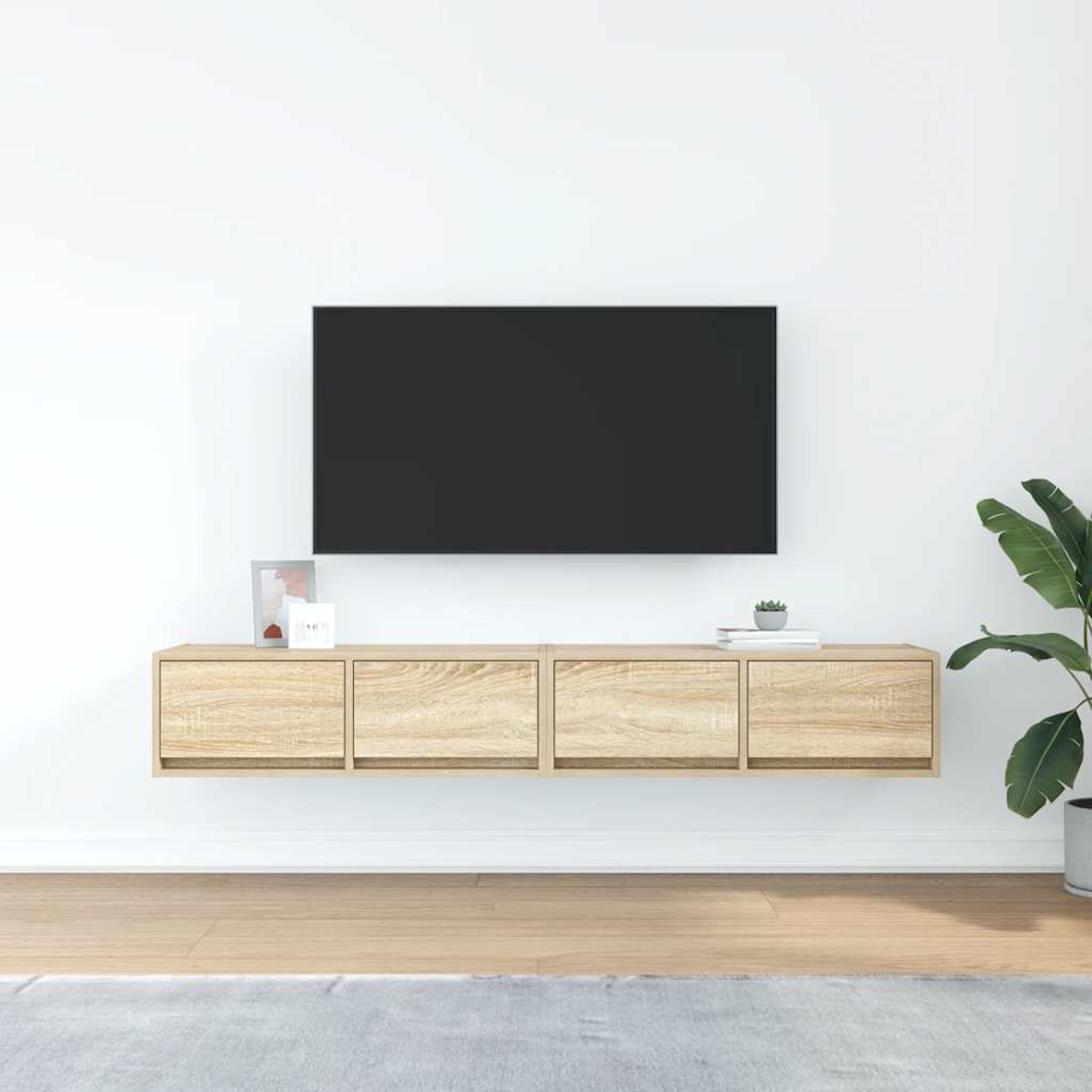 Ein schwebendes Holz-TV-Möbel mit einem schwarzen Fernseher darüber, daneben eine Pflanze.