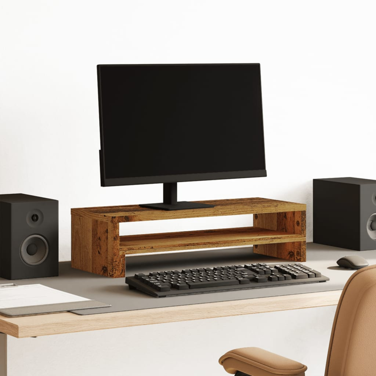 Ein Schreibtisch mit einem Monitor auf einem Holzständer, Tastatur und Lautsprecher.
