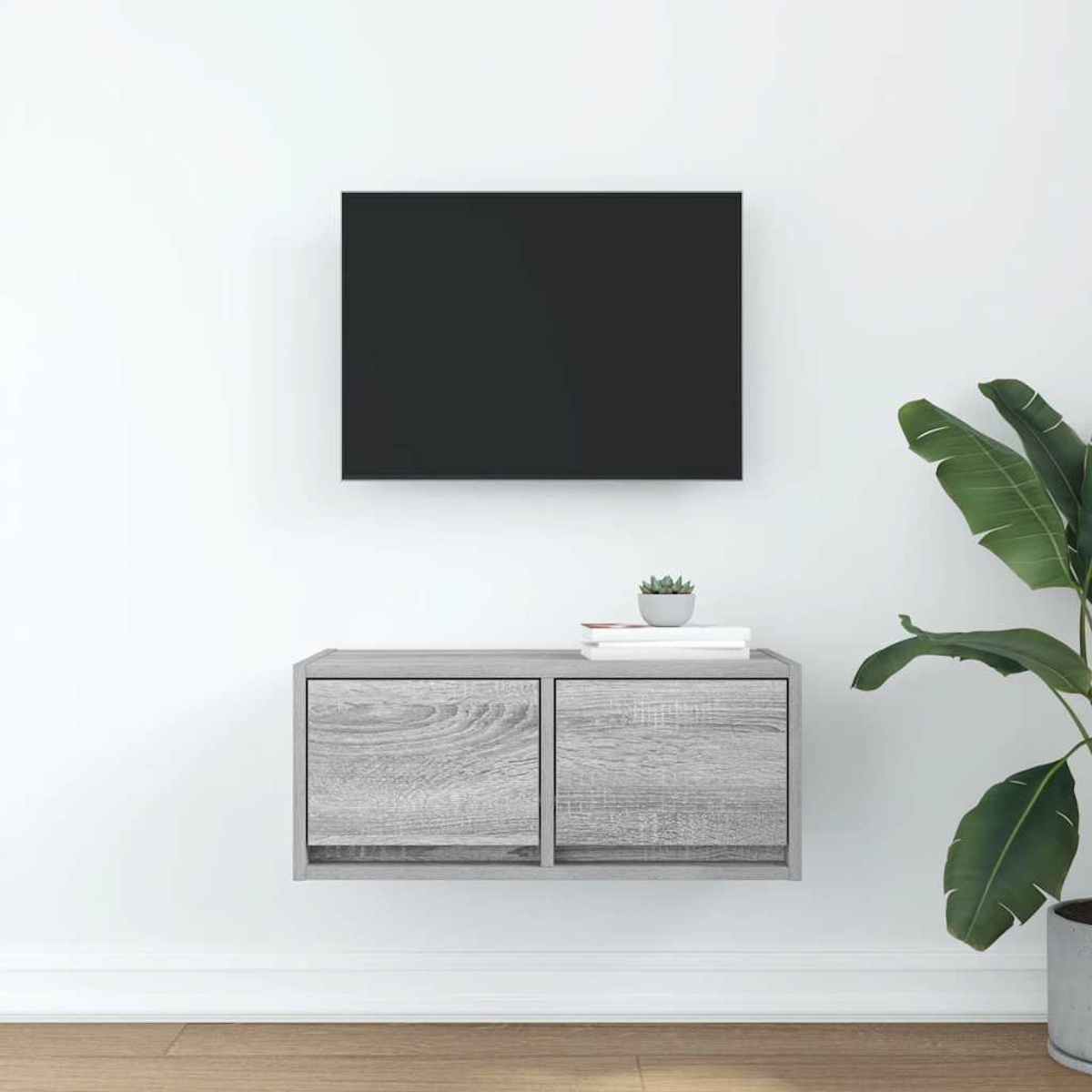 Ein Wand-TV-Schrank aus Holz mit zwei Türen, daneben eine Pflanze.